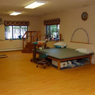 A spacious therapy room with a treatment table and stairs for rehabilitation exercises.