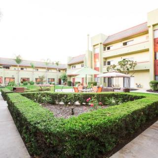 A hotel courtyard featuring manicured hedges and outdoor seating areas.