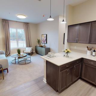 A modern apartment interior featuring an open floor plan with a kitchen and living room area.