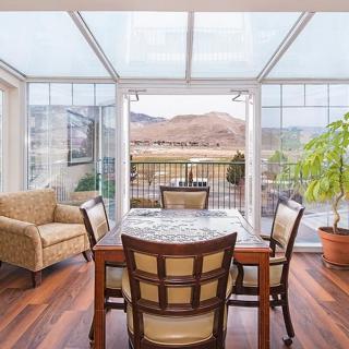 Bright sunroom with a dining set and indoor plants overlooking a scenic outdoor view.