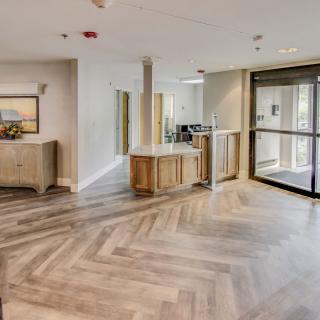 A modern lobby area with wooden flooring and a reception desk.