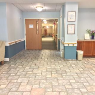 A tiled hallway interior with a closed wooden door and decorative furniture.