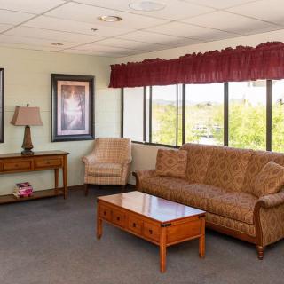 A cozy living room with a sofa, armchair, and coffee table by large windows.