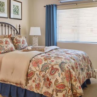 A cozy bedroom with floral bedding and blue curtains.