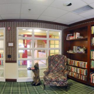 A cozy library corner featuring an armchair, bookshelves, and a decorative carpet.