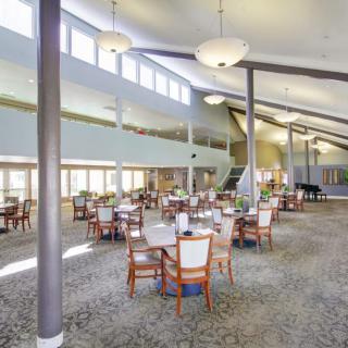 A spacious dining area with neatly arranged tables and chairs under ample lighting.