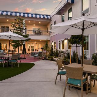 A beautifully landscaped courtyard featuring outdoor seating with umbrellas in the evening.