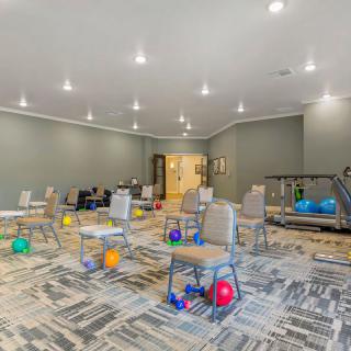 A spacious exercise room with chairs and fitness balls arranged on a carpeted floor.
