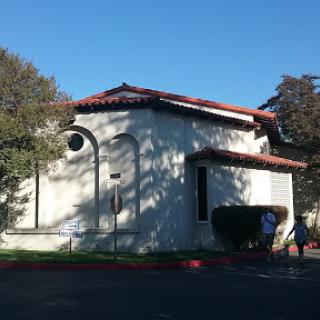 A unique architectural structure with a red-tiled roof, surrounded by trees under clear blue skies.