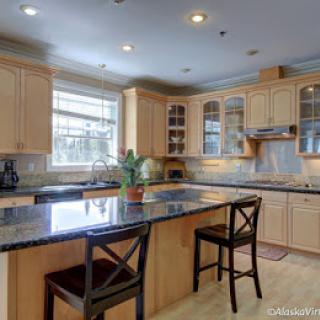 A modern kitchen with wooden cabinets and a central island with bar stools.
