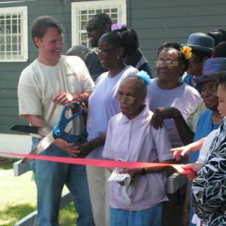 A group of people gather for a ribbon cutting ceremony at a community event.