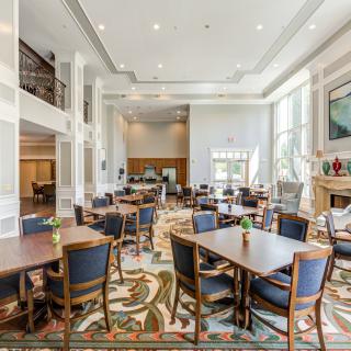 A spacious dining area with multiple tables and chairs, featuring large windows and bright lighting.