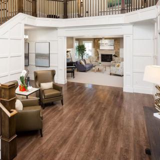 A spacious and elegant living room featuring hardwood floors, comfortable armchairs, and modern decor.