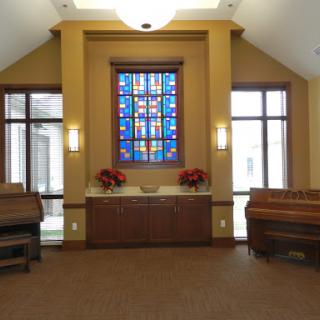 A serene interior space featuring a stained glass window and wooden furnishings.
