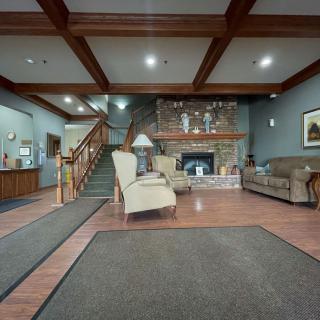 A welcoming lobby with comfortable seating, a fireplace, and wooden stairs leading to the upper floor.