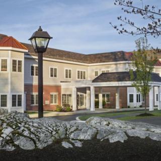 A two-story residential building with a lamp post and landscaped surroundings.