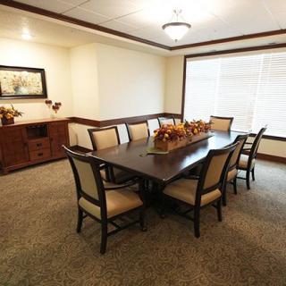 Elegant dining room with a large wooden table and chairs, featuring classic decor and ample natural light.