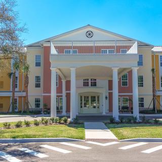 A residential building with a grand entrance featuring columns and landscaped surroundings.