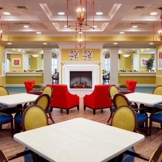 A vibrant seating area with colorful furniture, featuring a central fireplace and elegant lighting.