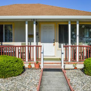 A small suburban house with a neatly manicured front yard and a welcoming front porch.