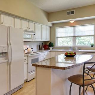 A bright and modern kitchen featuring white cabinetry, an island with seating, and plenty of natural light.