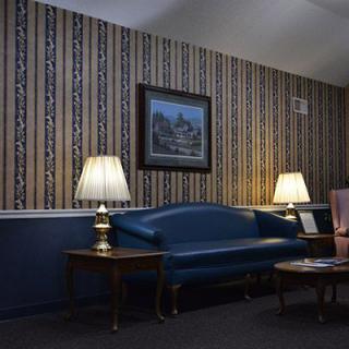 A vintage-style living room with a blue sofa, two lamps, and patterned wallpaper.