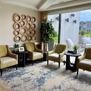 A cozy living room area with stylish chairs, decorative wall art, and a large window letting in natural light.