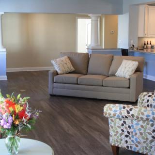 A modern living room with a comfortable sofa, armchair, and floral decorations.