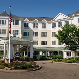 A view of a hotel exterior with neatly landscaped surroundings and a flagpole.