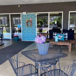 A cozy outdoor seating area featuring a vibrant blue door and beautifully arranged flowers.