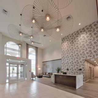 A modern lobby featuring a stylish chandelier and a decorated reception area.