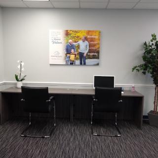 A modern office space featuring a desk, two chairs, and artwork on the wall.