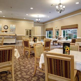 A well-lit dining room with arranged tables and chairs, featuring elegant decor and large windows.