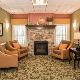 A cozy living room with a fireplace and comfortable armchairs arranged around it.