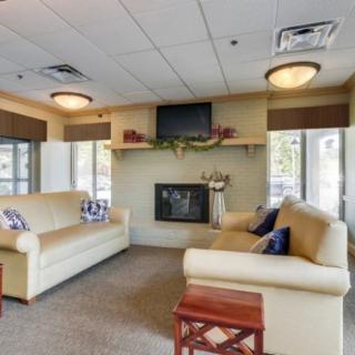 A cozy living room with two sofas, a fireplace, and a television mounted above it.