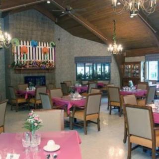 A cozy dining room with tables set for guests, featuring a fireplace and elegant chandeliers.
