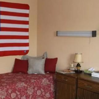 A cozy bedroom with a bed, pillows, and a flag on the wall.