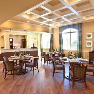 A stylishly designed restaurant dining area with tables and chairs, featuring natural lighting and wood flooring.