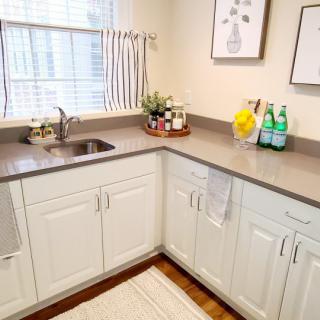A clean, modern kitchen with white cabinets and a gray countertop.