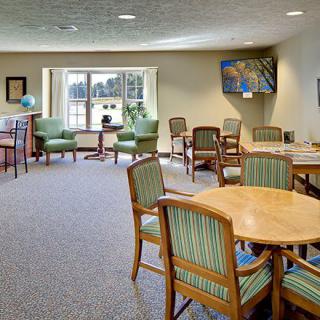 A spacious meeting room with tables and chairs, featuring large windows and artwork on the walls.