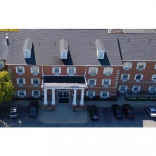 Aerial view of a brick building with a parking area in front.