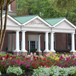 A building with classical columns surrounded by colorful flowers.