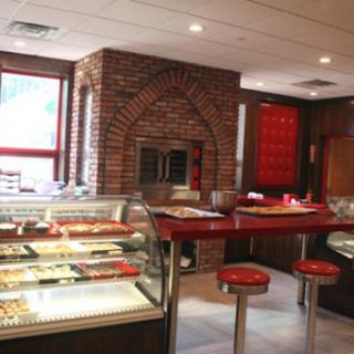 A cozy bakery featuring a brick wall and bright red dcor, showcasing an array of delicious desserts.