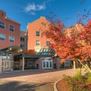 A brick building entrance surrounded by vibrant autumn foliage under a clear blue sky.