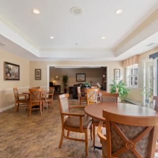 A spacious dining area with wooden tables and chairs, illuminated by natural light.