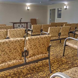 An empty conference room with rows of chairs and a microphone setup at the front.