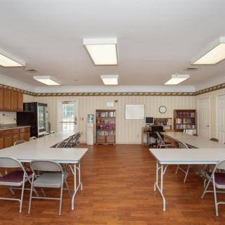 A multipurpose room with tables, chairs, and a kitchen area.