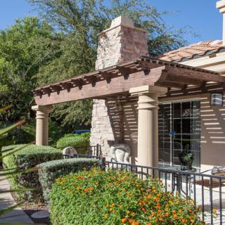 A beautiful house exterior with a pergola, columns, and lush landscaping.