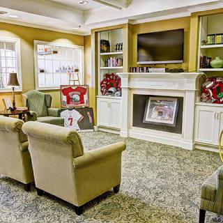 A cozy living room with comfortable seating, a fireplace, and a TV mounted above built-in bookshelves.