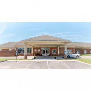 A brick building with a covered entrance and adjacent parking lot.